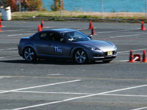 2001 Mercury Grand Marquis - A gray Mazda RX-8 navigates a course marked by orange cones on a sunny day.