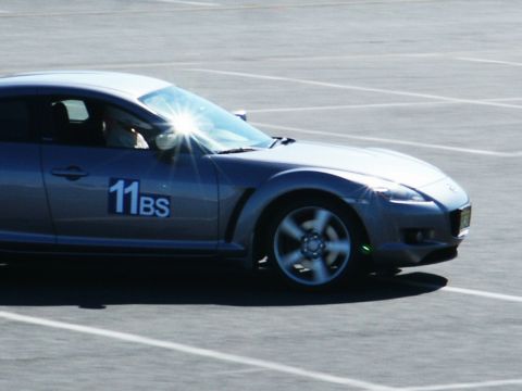 2001 Mercury Grand Marquis - A gray Mazda RX-8 is captured in motion on a paved surface.