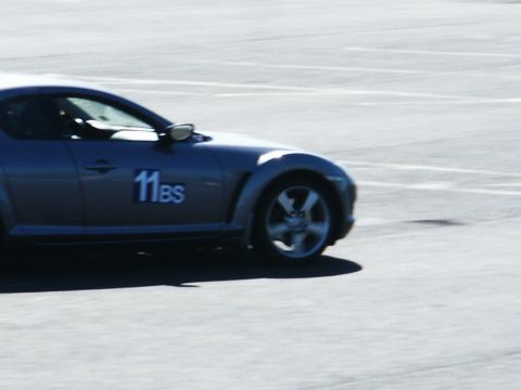 2001 Mercury Grand Marquis - A blue sports car with racing numbers is seen on a paved surface, possibly a track.
