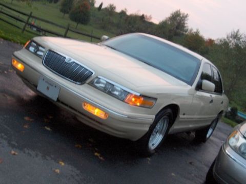 1996 Mercury Grand Marquis - A Mercury Grand Marquis is parked on a wet surface with fallen leaves, with another vehicle partially visible.