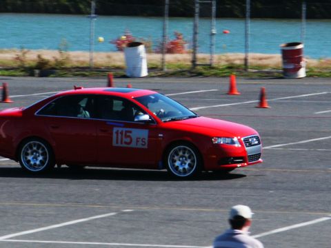 2001 Mercury Grand Marquis - A red sedan navigates a course marked by orange cones near a body of water.