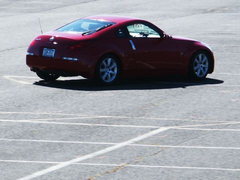 2001 Mercury Grand Marquis - Red Nissan 350Z coupe seen from the rear, parked on asphalt with painted lines.