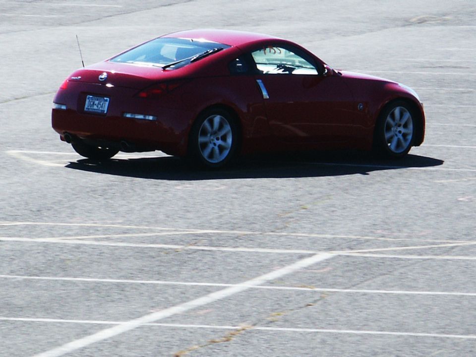 Red Nissan 350Z coupe, rear 3/4 view. License plate is JDM-641