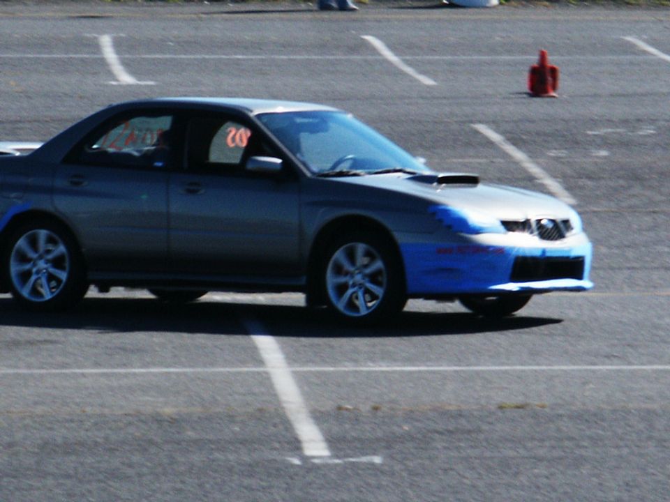 Silver Subaru Impreza WRX with blue tape on the front bumper and a scoop on the hood