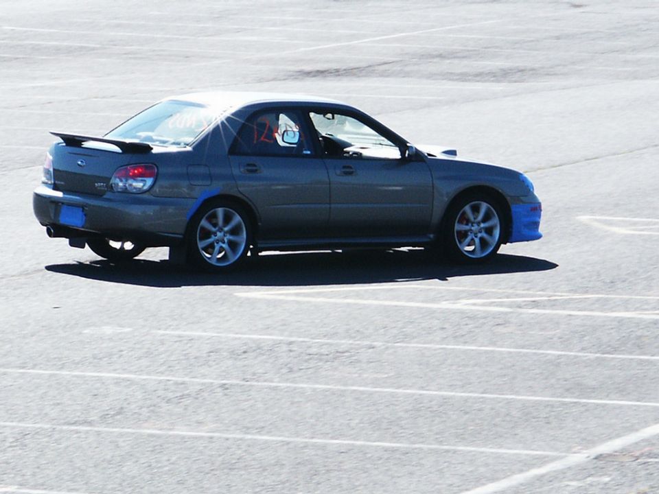 Gray Subaru Impreza WRX sedan with a rear spoiler and blue front bumper accents