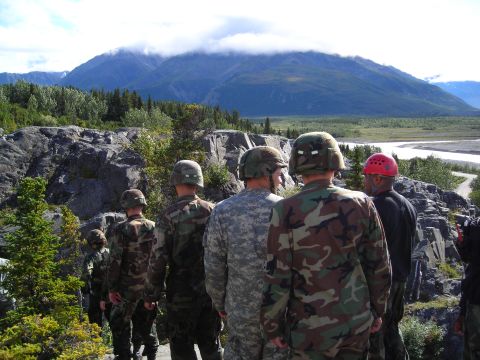 2003 Jeep TJ - A group of soldiers observe a vast landscape under a cloudy sky.