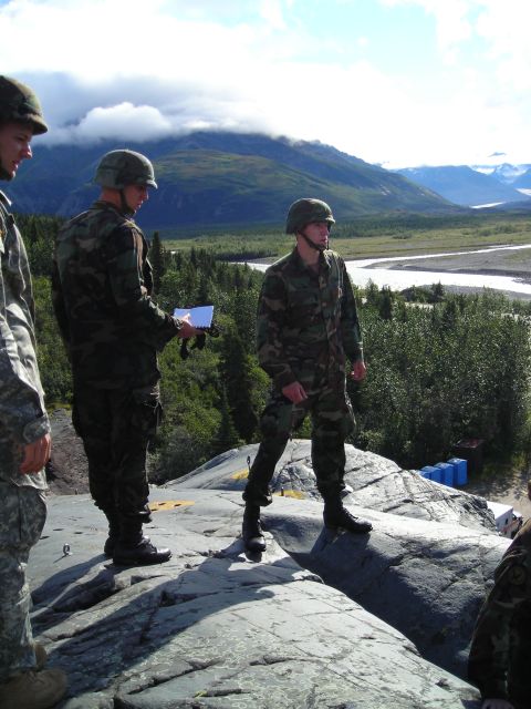 2003 Jeep TJ - Soldiers observe a vast river valley and mountainous terrain under a cloudy sky.