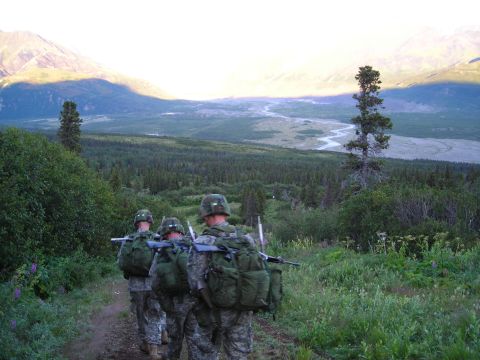 2003 Jeep TJ - Soldiers trek through a vast, mountainous landscape under a bright sky.