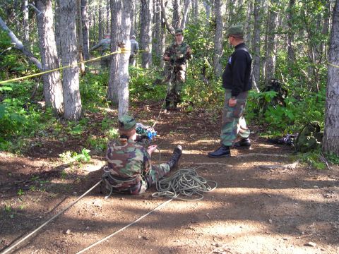 2003 Jeep TJ - A group of soldiers appears to be engaged in a rope-handling training exercise in a forest setting.