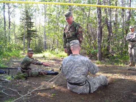2003 Jeep TJ - Military personnel train with ropes in a forest setting, with instructors observing.
