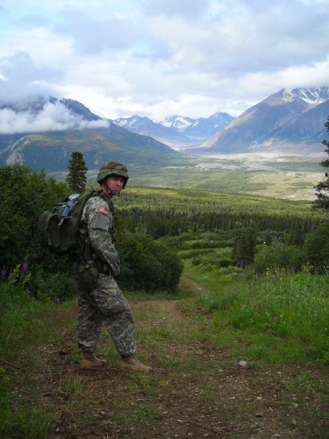 2003 Jeep TJ - A soldier stands on a path with a vast mountainous landscape in the background.