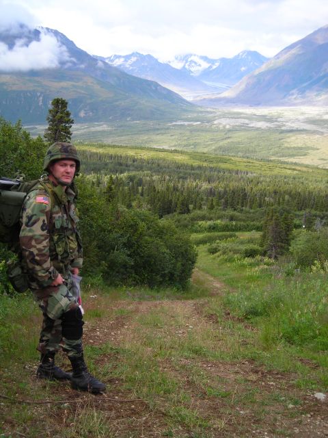 2003 Jeep TJ - A soldier in camouflage stands on a dirt path overlooking a vast valley with mountains in the distance.