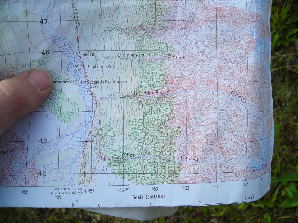 Printed topographic map of Alaskan creeks and rapids held in hand
