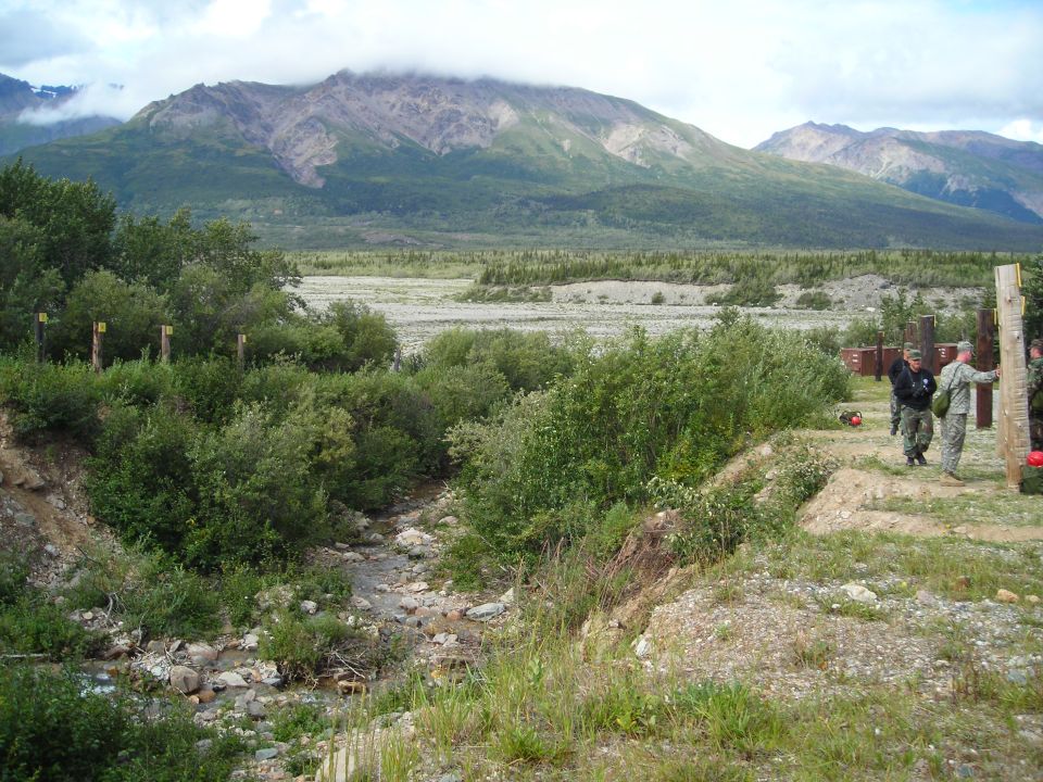 Mountainous landscape with a dry riverbed and people in military uniforms