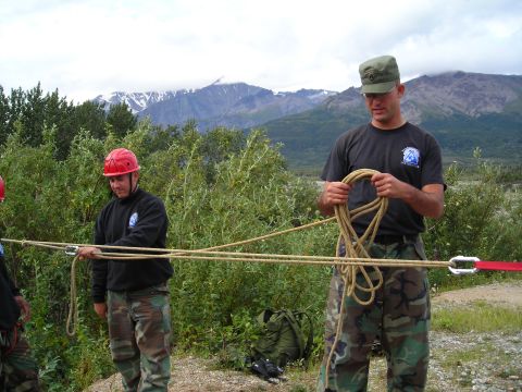 2003 Jeep TJ - Two individuals are engaged in rope work with a mountainous landscape behind them.