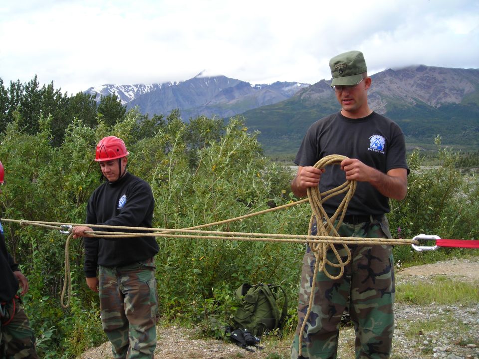 Men handling ropes outdoors with mountains in background