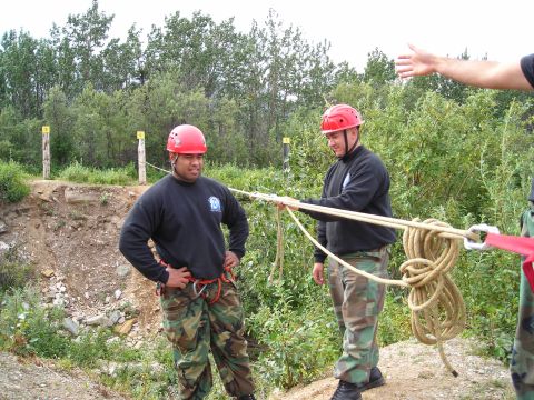 2003 Jeep TJ - Two individuals in safety helmets and gear are engaged in a rope-handling activity outdoors.