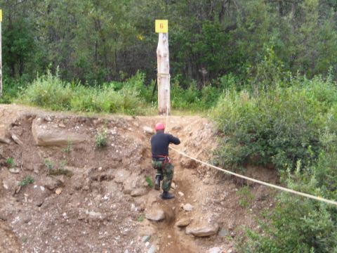 2003 Jeep TJ - A person uses a rope to descend a steep, rocky slope, with numbered posts visible in the background.