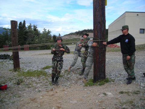 2003 Jeep TJ - Soldiers participate in a training exercise involving ropes and a wooden pole outdoors.