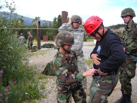 2003 Jeep TJ - Soldiers in camouflage uniforms and helmets practice rappelling outdoors with mountains in the background.