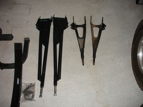 1996 Ford Bronco - A pair of black suspension control arms and two used control arms are laid out on a concrete floor.