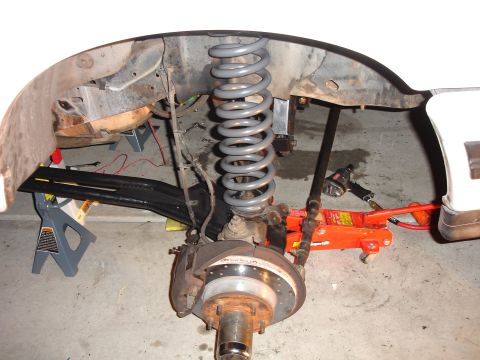 1996 Ford Bronco - The vehicle's front suspension system is shown disassembled, with parts supported by jack stands and a hydraulic jack.