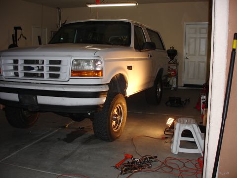 1996 Ford Bronco - Front view of a white 1996 Ford Bronco in a garage, possibly undergoing maintenance.