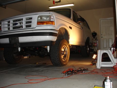 1996 Ford Bronco - A white Ford Bronco is shown in a garage, possibly undergoing maintenance or modification.