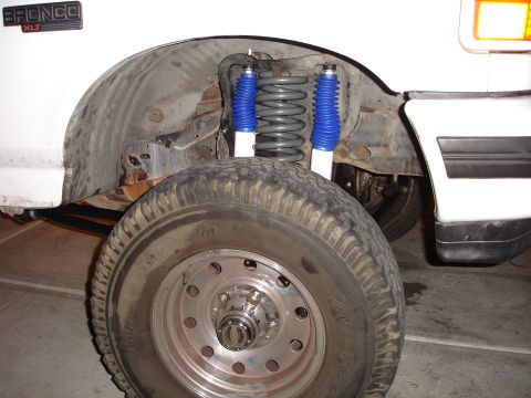 1996 Ford Bronco - Close-up of the front suspension of a white 1996 Ford Bronco XLT, showing new shocks and springs.