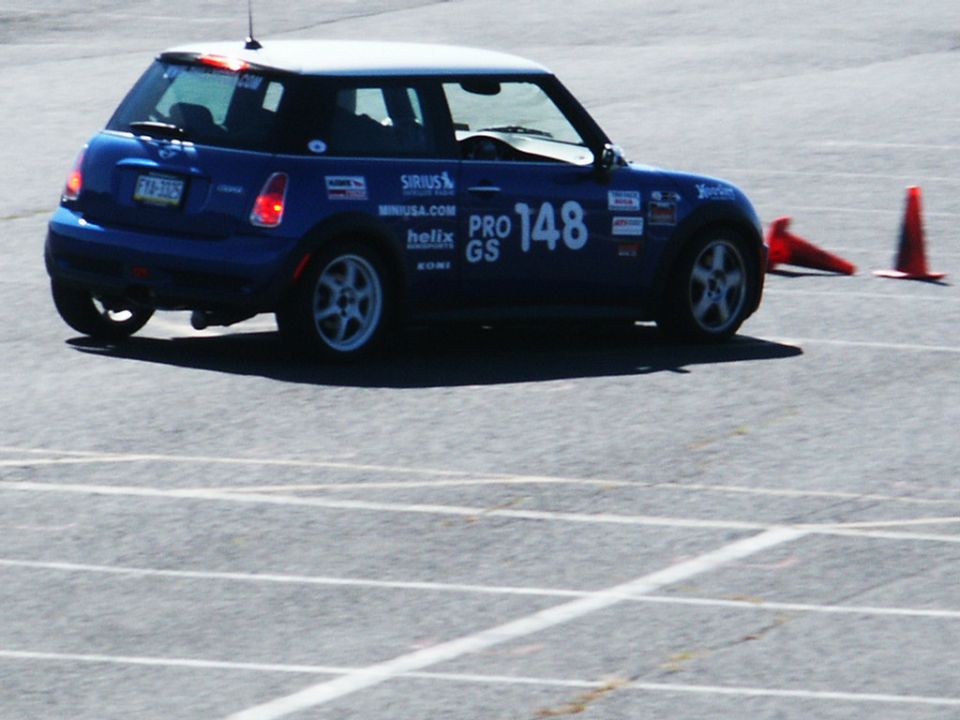 Blue Mini Cooper with white roof, number 148, and various sponsor decals on a race track