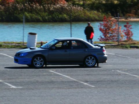2001 Mercury Grand Marquis - A gray Subaru Impreza WRX sedan with a blue front bumper is seen on an asphalt surface near a body of water.