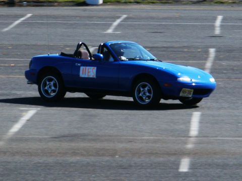 2001 Mercury Grand Marquis - Blue Mazda Miata with "MES" on door is seen on a paved track.