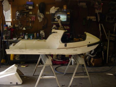 1995 Ford Mustang - A white personal watercraft body is disassembled and supported by sawhorses in a cluttered garage setting.