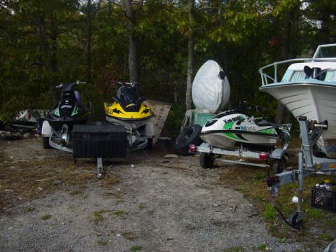 1995 Ford Mustang - Multiple jet skis and a boat are parked outdoors on trailers.