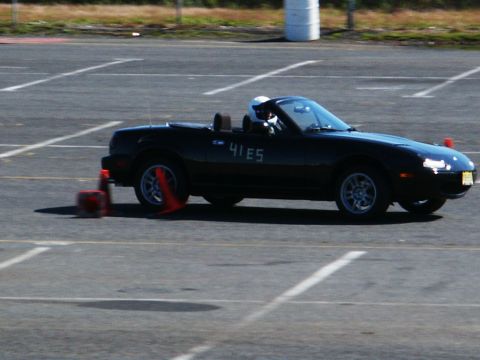 2001 Mercury Grand Marquis - A black Mazda Miata is seen on a track, navigating around orange cones during an event.