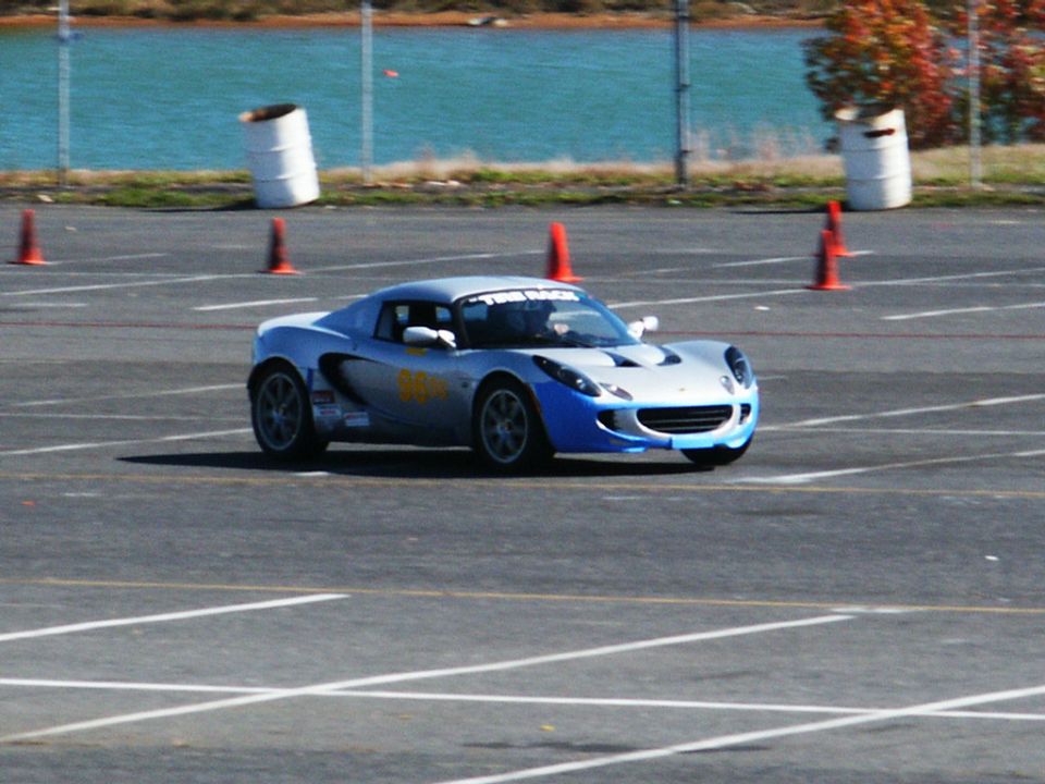 Silver and blue sports car on a race track with yellow racing decals