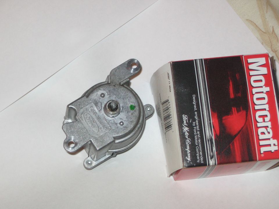 Cast aluminum Ford actuator/motor part with Ford logo beside a red Motorcraft parts box