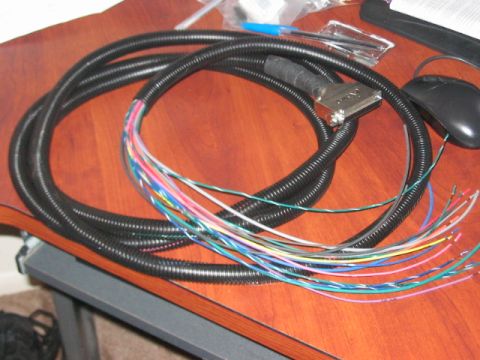 1991 Ford Bronco - A wiring harness with many colored wires and a metal connector is shown on a desk.