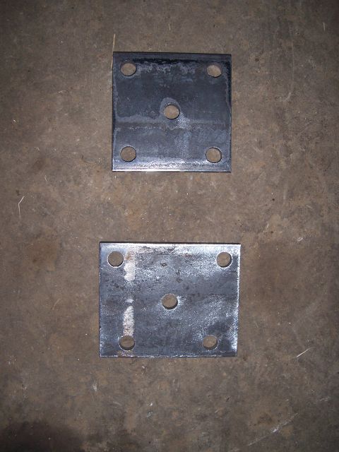 1983 Ford Bronco - Two metal plates with bolt holes are shown on a concrete surface.