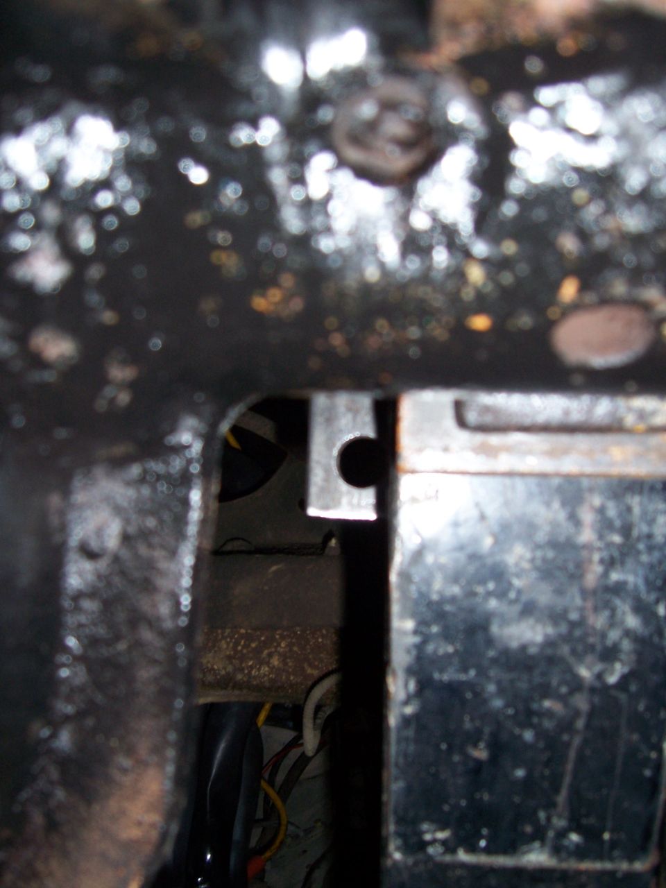 Close-up of metal brackets and wiring, possibly from a vehicle's undercarriage