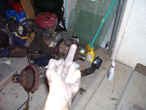 1991 Ford Bronco - A disassembled vehicle axle assembly is shown in a cluttered garage environment.