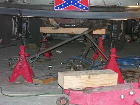 1991 Ford Bronco - The underside of a vehicle is supported by jack stands, with a Confederate flag plate mounted above.
