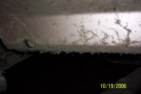 1996 Ford Bronco - A close-up view of the underside of a vehicle, revealing accumulated debris and rust.