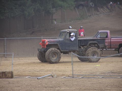 1995 Ford Bronco - Modified pickup truck with large tires and a driver in a helmet at an off-road park.
