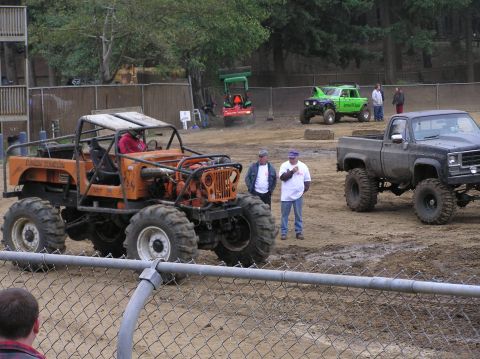 1995 Ford Bronco - Several modified off-road vehicles are gathered at an outdoor event, possibly a mud park.