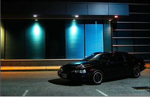 1997 Ford Thunderbird - A black 1997 Ford Thunderbird is parked in front of a building with blue and teal lighting.