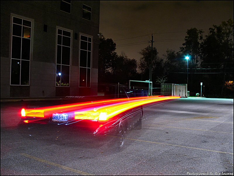 Car taillights create light streaks as it moves at night. License plate ARBJ-913 is visible