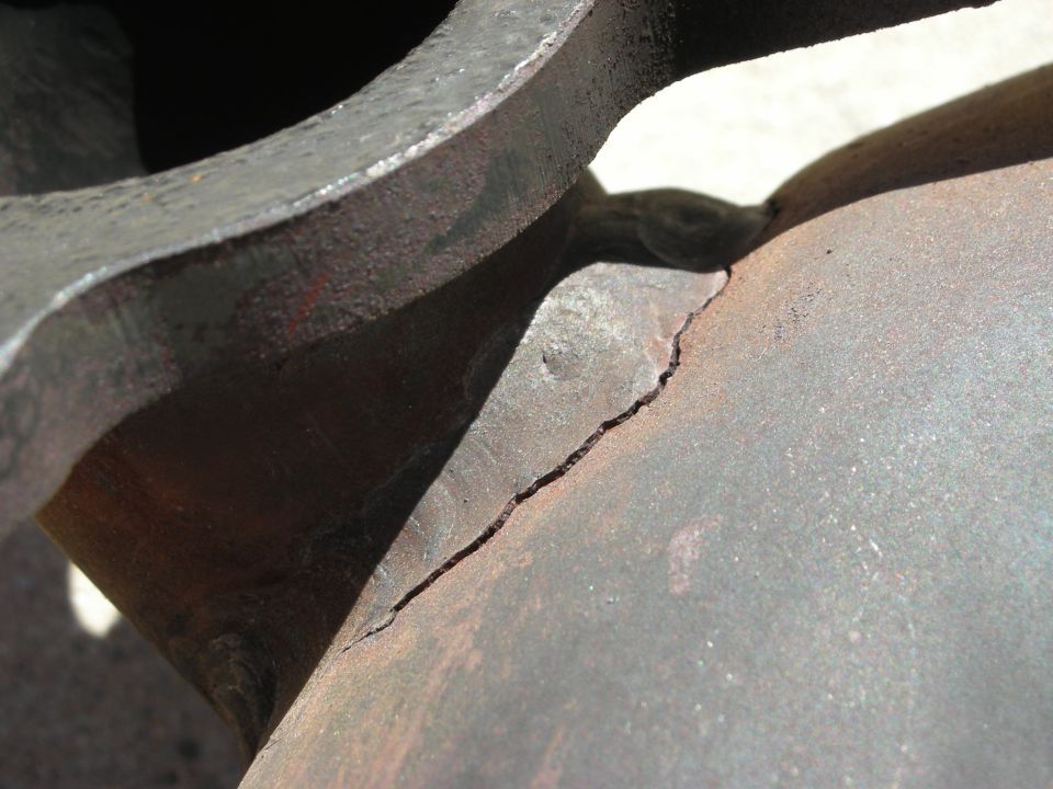 Close-up of a cracked metal component, possibly exhaust or suspension