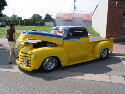 1993 Ford Taurus - A yellow and black pickup truck is displayed with its hood open at an outdoor event.