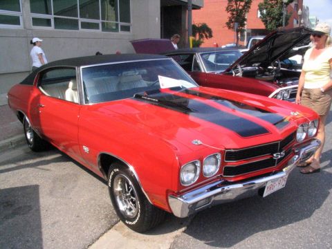 1993 Ford Taurus - A classic red muscle car is parked on the street, with another vehicle behind it.